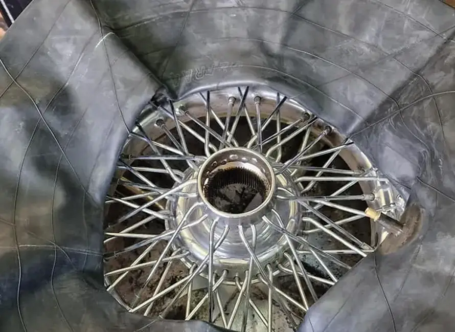 A damaged inner tube is shown partially wrapped around the spokes of a metal bicycle wheel hub, highlighting the need for professional Tyre Repair Weymouth services.
