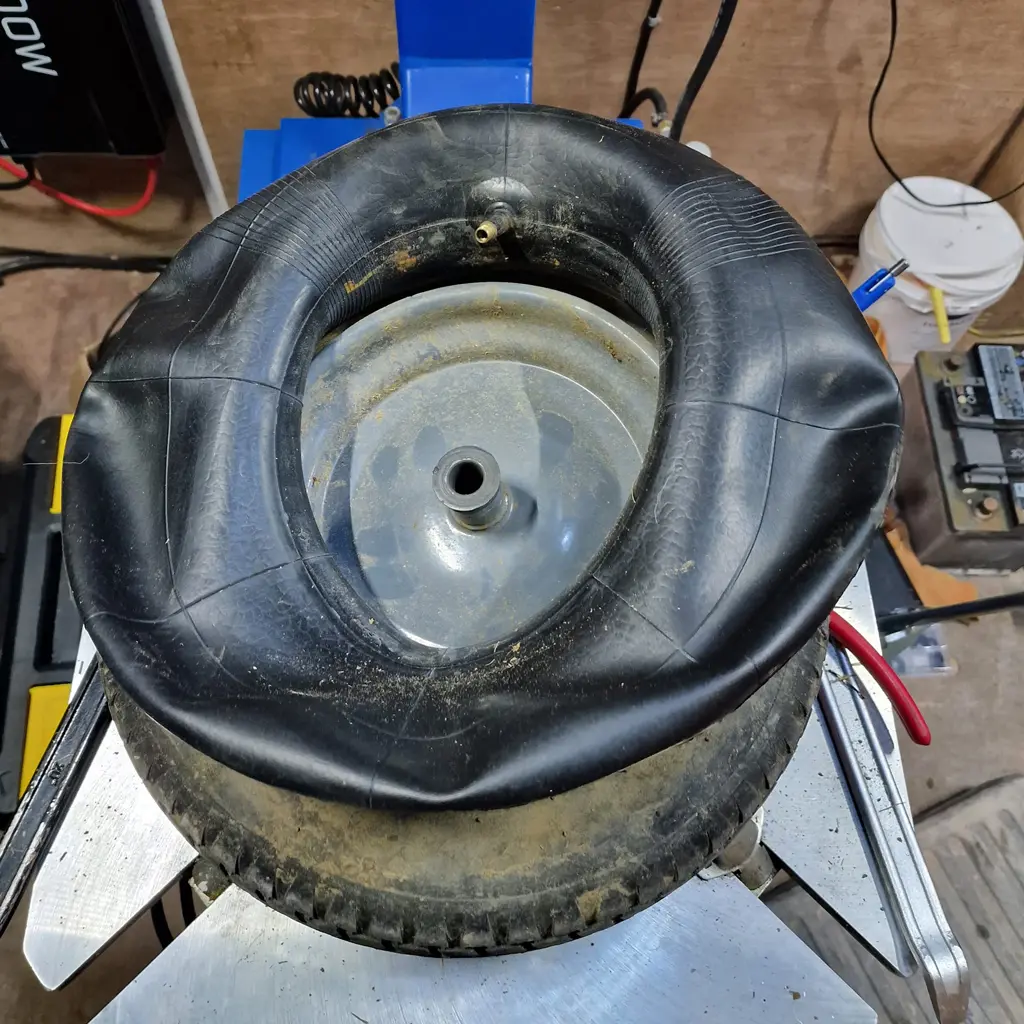 A deflated inner tube rests atop a small, dirty tire on a metal workbench in the workshop at Coastal Tyre Services.